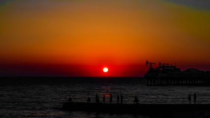 Obraz premium Fishermen on sunset background in the sea