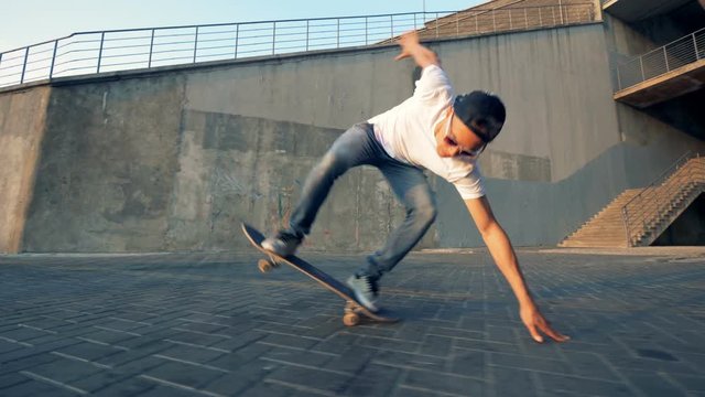Skater falling off a board. Teenager jumps on a skateboard and falls off on a road.