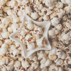 Fototapeta na wymiar Some homemade Popcorn as detailed close-up shot, star shaped bowl, top view. Instagram matte filter.