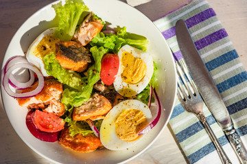 Healthy diet salad with salmon, tomatoes, eggs, onion and lettuce, top view. Dietary lunch