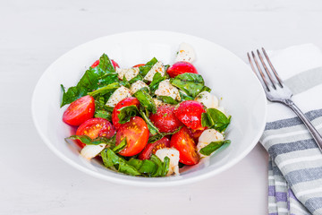 Italian food - Healthy caprese salad with mini mozzarella, cherry tomatoes and basil