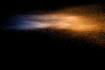 Blue orange dust particles explosion on black background. Color powder dust splash.