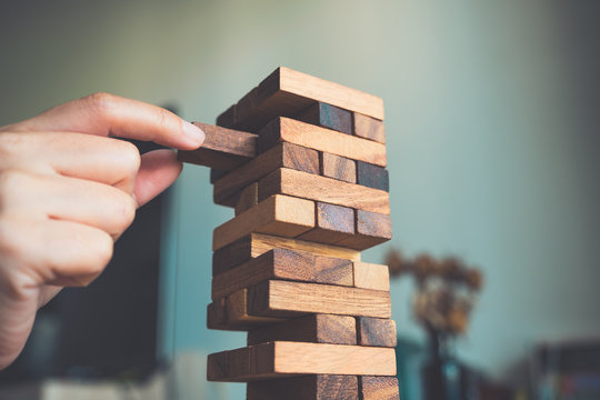 Closeup image of a hand holding and playing Jenga or Tumble tower wooden block game