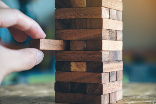 Closeup Image Of A Hand Holding And Playing Jenga Or Tumble Tower Wooden Block Game