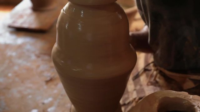 Man's hands make a clay pitcher.