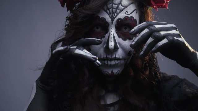 Make-up for Halloween, sugar Mexican skull, make-up. The girl beckons to herself. Slow motion