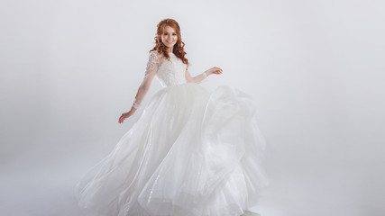 Fototapeta na wymiar Lovely young woman bride in a lavish wedding dress. Light background.