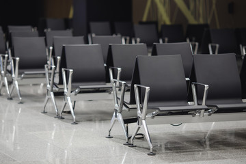 Waiting area with black chrome-plated chirps stands in row airport lobby.