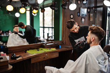 Handsome bearded man at the barbershop, barber at work.