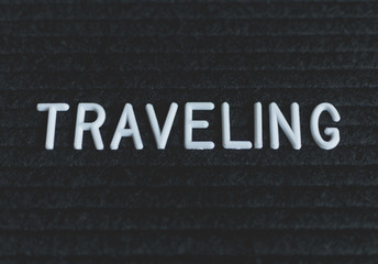 Word traveling written on the letter board. White letters on the black background. Business concept