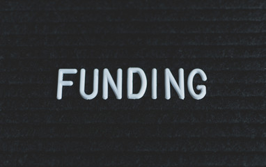 Word funding written on the letter board. White letters on the black background. Business concept
