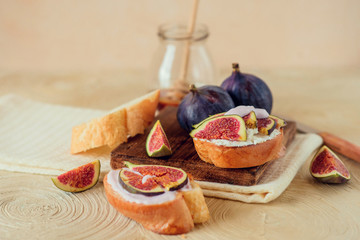 Autumn dessert: sweet toast with ripe figs, soft cheese and honey on a light background.