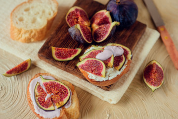Autumn dessert: sweet toast with ripe figs, soft cheese and honey on a light background.