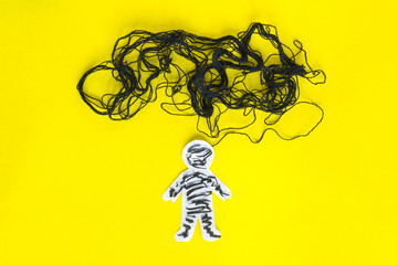 Negative thinking  concept, paper man and black thread on the yellow background.