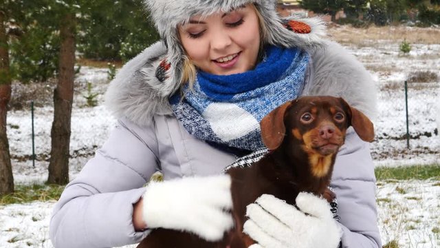 Young woman playing with her little puppy dog outdoor during winter weather