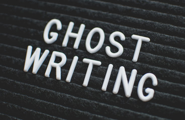 Words ghost writing written on the letter board. White letters on the black background.