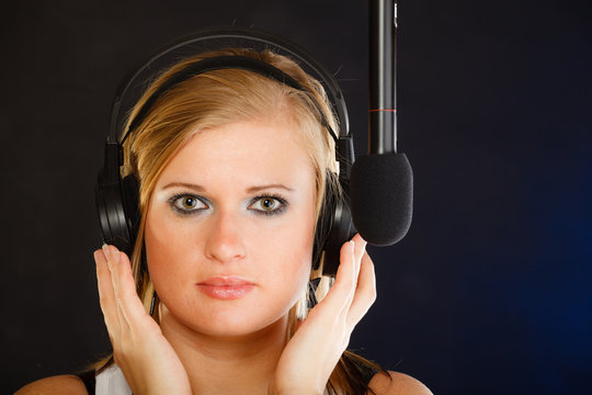 Woman singing to microphone wearing headphones in studio