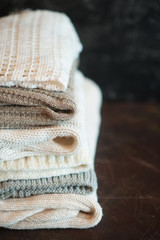 A stack of textured knitted things of light colors. The concept of comfort, warmth.