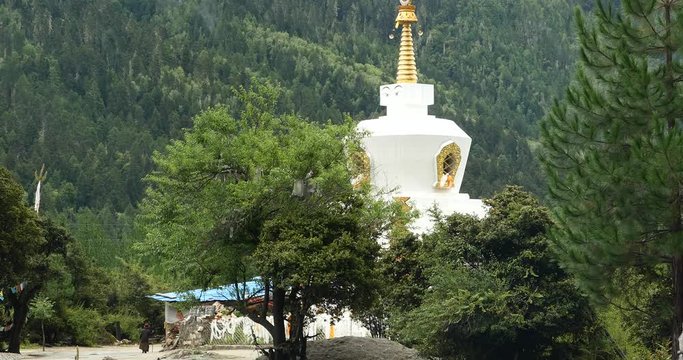 4k tibet people walking around buddhist white stupa in village,cloud cover mountain.