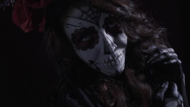 Charming brunette in a makeup of a sugar skull for halloween, close up