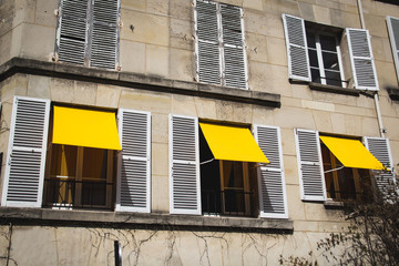 Three yellow window shutters on an apartment in Paris France