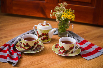 Tea ceremony, filled tea in service with wildflowers on the wood texture