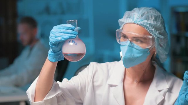 Scientist in mask holding a flask with methyl