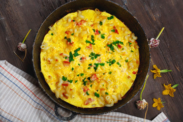 Traditional rustic omelette with bacon, pasta and greens .  Copy space