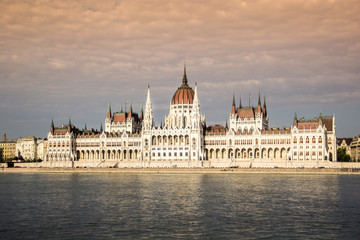 Parliament building in Budapest with clouds and water reflection at golden hour