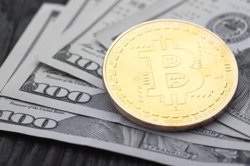 Gold Bitcoin on hundred dollars bills.