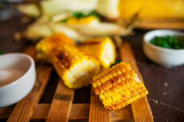 Grilled corn with herbs and spices on a dark background.