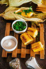 Grilled corn with herbs and spices on a dark background.