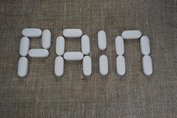 white oval tablets, laid out in the form of the word "pain"