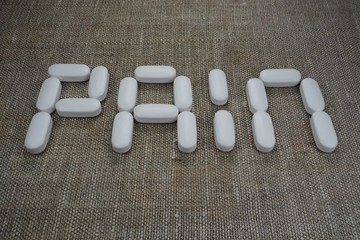 white oval tablets, laid out in the form of the word "pain"