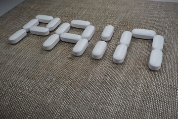 white oval tablets, laid out in the form of the word "pain"