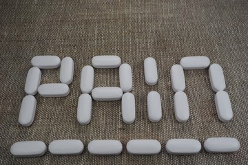 white oval tablets, laid out in the form of the word "pain"