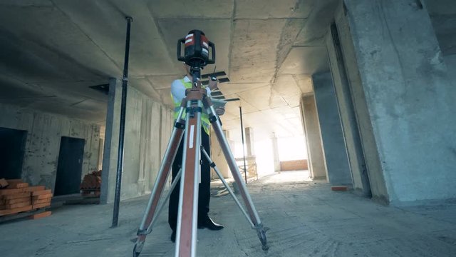 Architect with tablet uses a walkie talkie, standing in the unfinished building.