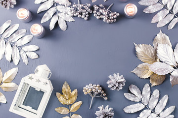 Winter concept flat lay with lantern, candles and silver leaves, copy space