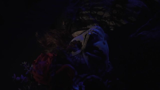 Dead girl in the makeup Santa Muerta lies in the dark, a wreath on her head