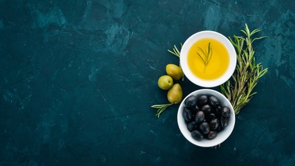 A set of olives and olive oil and rosemary. Green olives and black olives. On a black stone...