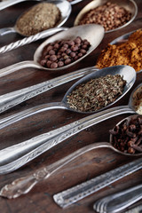 Different spices in  spoons on a wooden background.