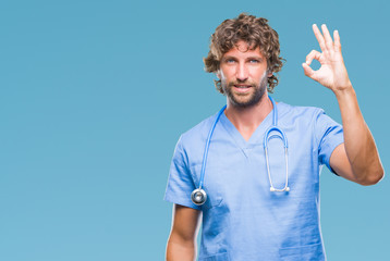Handsome hispanic surgeon doctor man over isolated background smiling positive doing ok sign with hand and fingers. Successful expression.