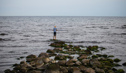 Fototapeta na wymiar A caucasian boy standing at the edge of a natrual pier in the baltic