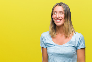 Young beautiful woman over isolated background looking away to side with smile on face, natural expression. Laughing confident.