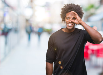 Afro american man over isolated background doing ok gesture with hand smiling, eye looking through fingers with happy face.