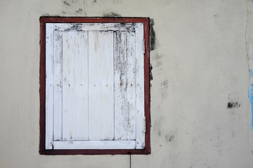 Old aged white window frame on rusted grey white cement wall paint in Thailand