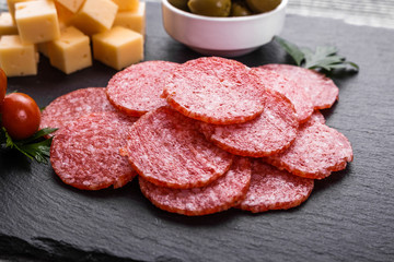 delicious sliced salami on a stone plate wooden background