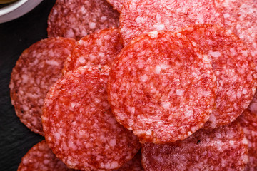 delicious sliced salami on a stone plate wooden background