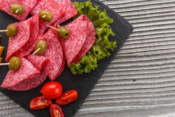 delicious sliced salami on a stone plate wooden background