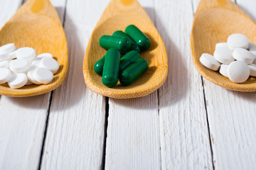 medicament pills on bamboo spoon, white wood table